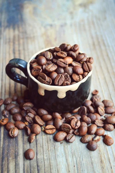 Copa llena de granos de café en la mesa de madera — Foto de Stock