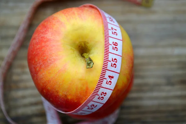 Conceito de dieta com maçã vermelha e fita métrica azul na mesa de madeira — Fotografia de Stock