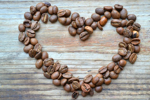 Grains de café torréfiés en forme de coeur sur fond de bois — Photo