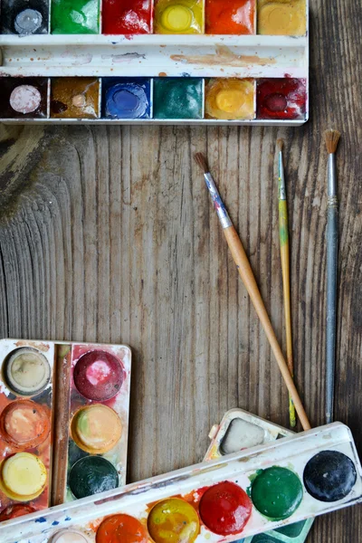 Pinturas y pinceles coloridos dispuestos como un marco en la mesa de madera —  Fotos de Stock