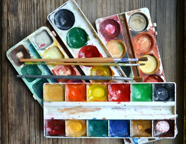 Färgglada färger och penslar på träbord — Stockfoto