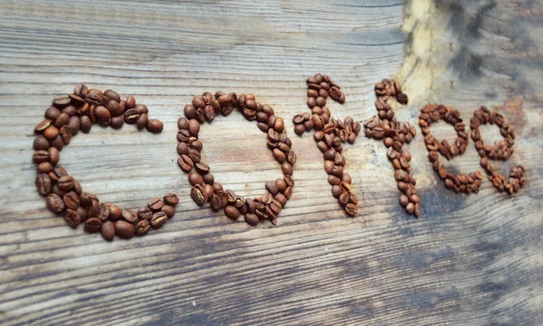 Mot "café" écrit sur les grains de café sur une table en bois — Photo