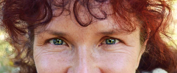 Mujer hermosa feliz con el pelo rojo en sus cuarentas oliendo al aire libre — Foto de Stock