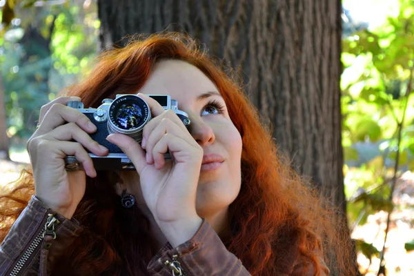 Mujer pelirroja joven con cámara retro tomando fotos — Foto de Stock