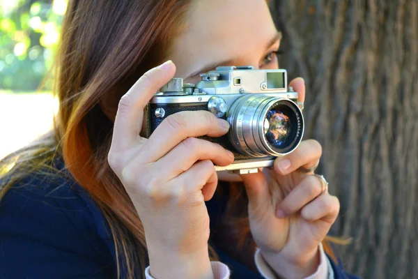 Mujer pelirroja joven con cámara retro tomando fotos — Foto de Stock