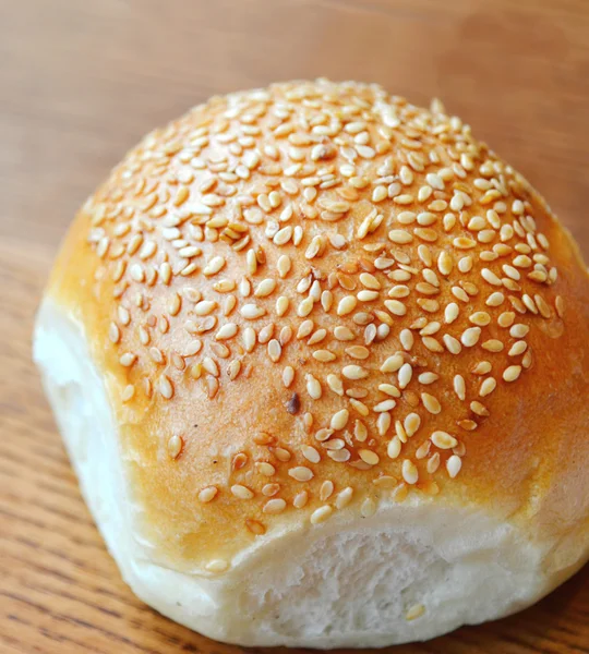 Pão saboroso com sementes de gergelim na mesa de madeira — Fotografia de Stock