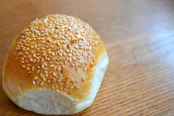 Pão saboroso com sementes de gergelim na mesa de madeira — Fotografia de Stock