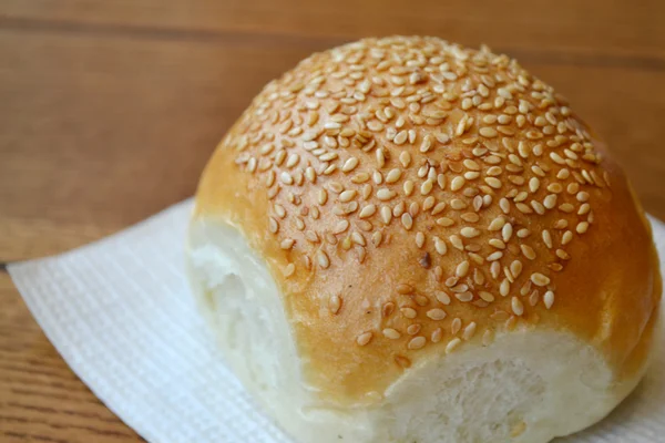 Leckeres Brötchen mit Sesam auf Holztisch — Stockfoto