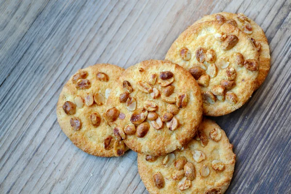 Tasty biscuits with candied peanuts on wooden table — Stock Photo, Image