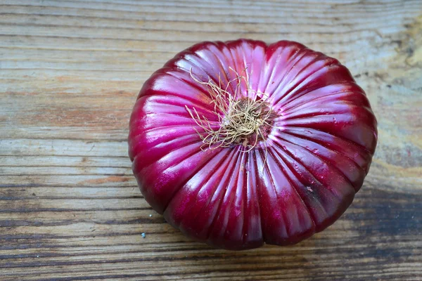 Velké červené cibule na dřevěný stůl — Stock fotografie