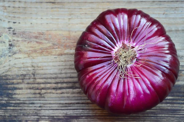 Velké červené cibule na dřevěný stůl — Stock fotografie