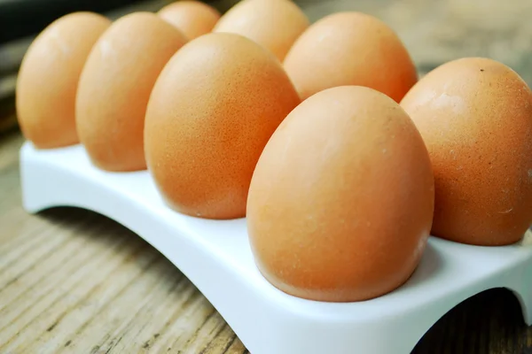 Hnědá vejce v košíku na dřevěný stůl — Stock fotografie