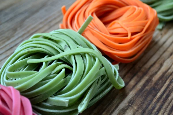 Färgglada okokt italiensk pasta på träbord — Stockfoto