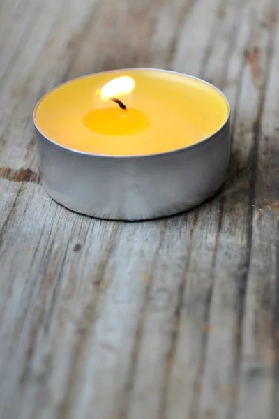Small yellow candle on wooden table — Stock Photo, Image