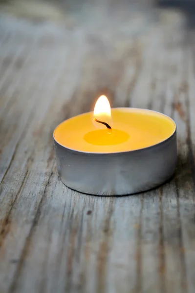 Small yellow candle on wooden table — Stock Photo, Image