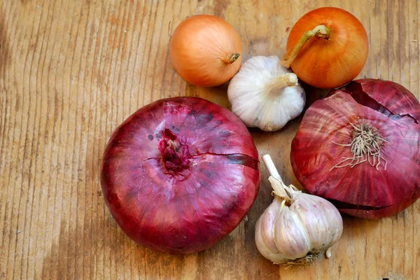 Red and bulb onions with whole organic garlic on wooden table — Stock Photo, Image