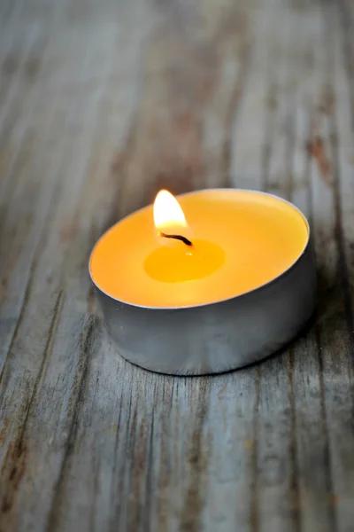 Malá žlutá svíčka na dřevěný stůl — Stock fotografie