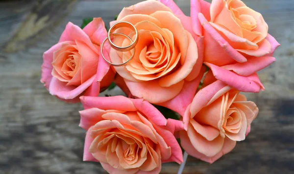 Dois anéis dourados de noivado em um lindo buquê de casamento de rosas rosa — Fotografia de Stock