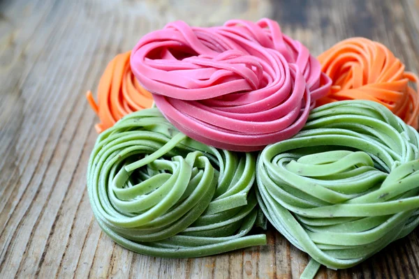 Colorful uncooked italian pasta on wooden table — Stock Photo, Image