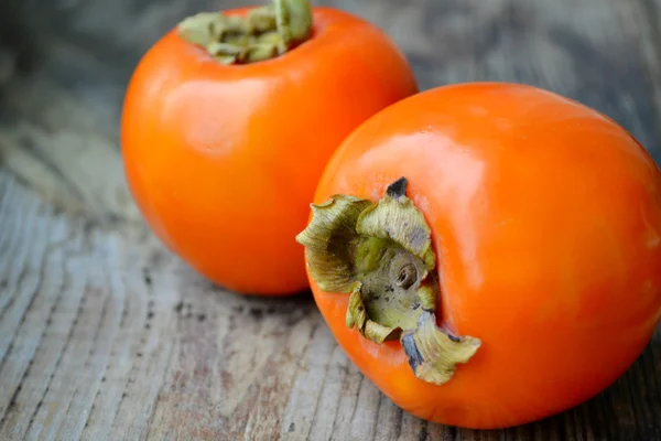 Delicious orange persimmons on wooden table — Stock Photo, Image