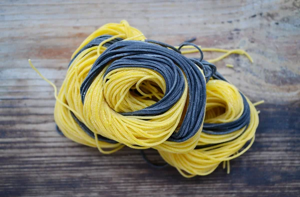 Bunte ungekochte italienische Pasta auf Holztisch — Stockfoto