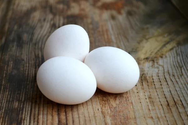 Três ovos brancos na mesa de madeira — Fotografia de Stock