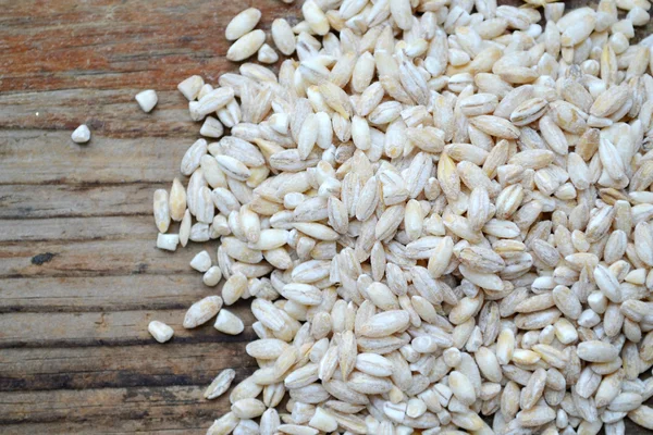 Pearl barley grains on wooden table — Stock Photo, Image