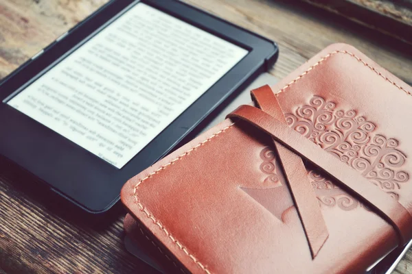 Black ereader with an old notebook in leather cover on wooden table — Stock Photo, Image