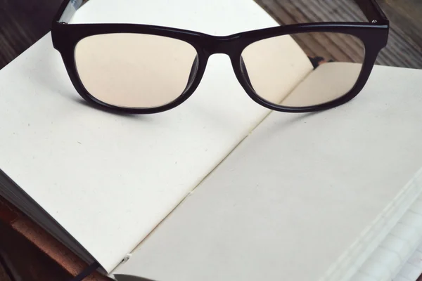 Un carnet rétro vide avec vieux papier, lunettes et housse en cuir — Photo