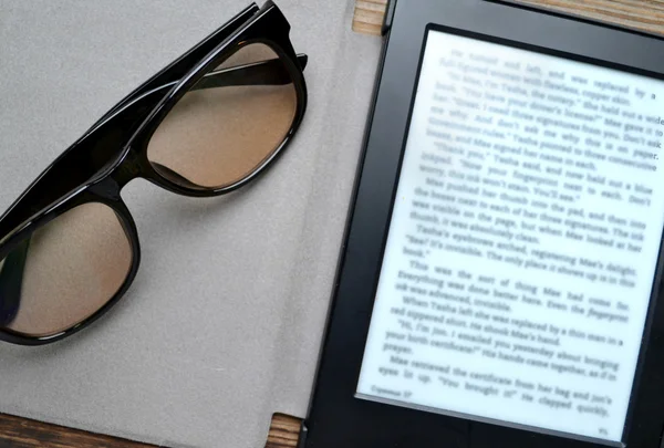 Black ereader with retro glasses on wooden table — Stock Photo, Image