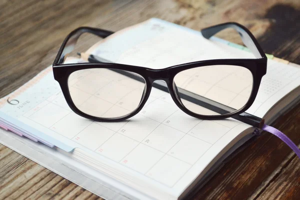 Un planificador diario retro vacío con lápiz negro y gafas de lectura —  Fotos de Stock