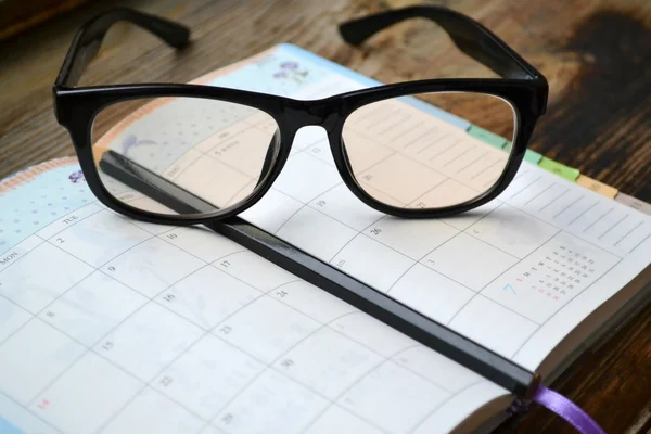 Un planificador diario retro vacío con lápiz negro y gafas de lectura —  Fotos de Stock