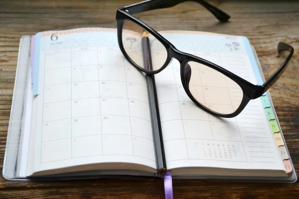 Egy üres retro napi tervező fekete ceruza és olvasó szemüveg — Stock Fotó