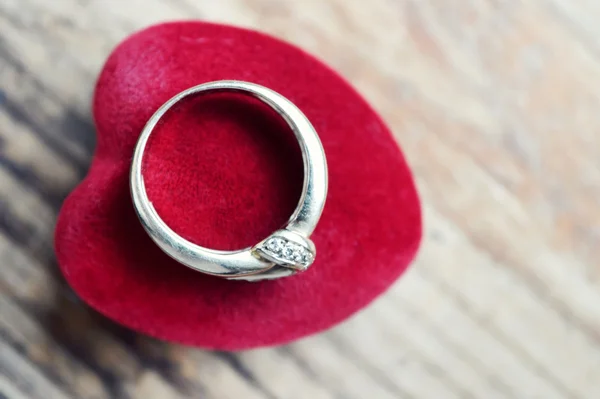 Caja de anillo en forma de corazón rojo con anillo de compromiso de platino en mesa de madera — Foto de Stock