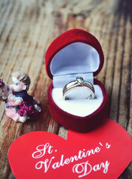 Boîte à bague en forme de coeur rouge avec bague de fiançailles en platine, anges et carte de Saint-Valentin sur table en bois — Photo