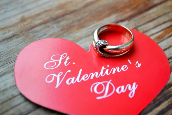 Coração vermelho em forma de cartão de Valentim com anel de noivado de platina na mesa de madeira — Fotografia de Stock