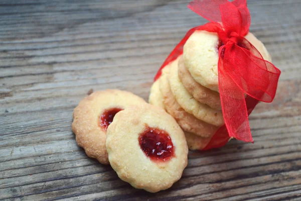 Homemade jam cookies with red ribbon bow on wooden table — Stock Photo, Image