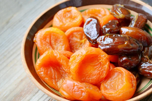 Dried apricots and brown dates fruit on wooden table — Stock Photo, Image