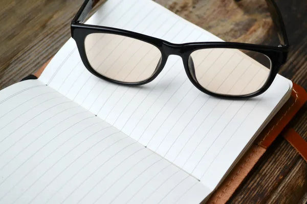 Un cuaderno retro vacío con papel viejo, gafas de lectura y funda de cuero — Foto de Stock