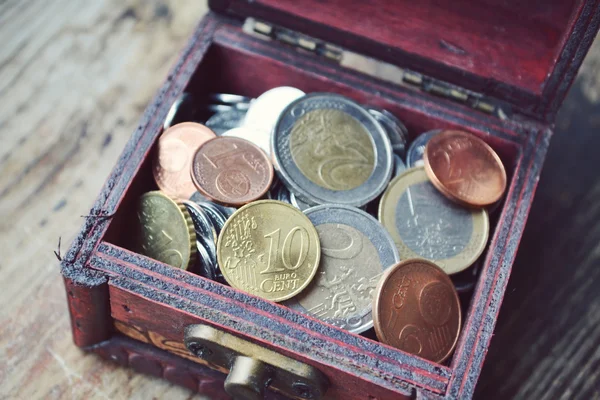 Little treasure chest with euro coins on wooden table