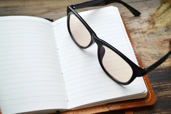 Un cuaderno retro vacío con papel viejo, gafas y funda de cuero — Foto de Stock