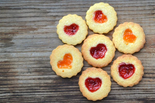 Ahşap masa üzerinde kalp şeklinde reçelli ev yapımı kurabiye