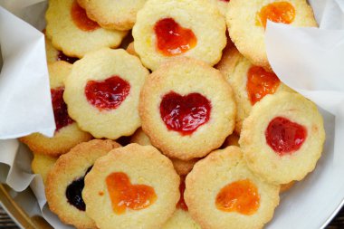 Ahşap masa üzerinde kalp şeklinde reçelli ev yapımı kurabiye