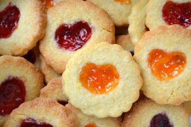 Ahşap masa üzerinde kalp şeklinde reçelli ev yapımı kurabiye