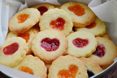 Ahşap masa üzerinde kalp şeklinde reçelli ev yapımı kurabiye