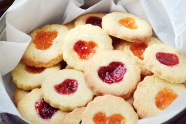 Ahşap masa üzerinde kalp şeklinde reçelli ev yapımı kurabiye