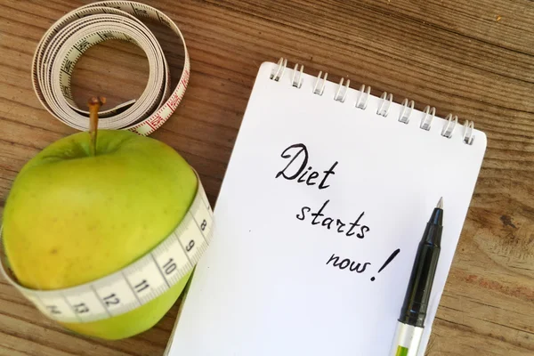 Diet concept with green apple, a notebook and a measuring tape on wooden table — Stock Photo, Image