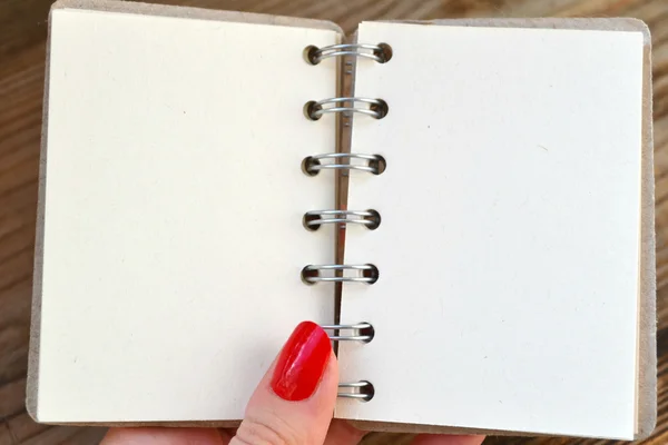 Mooie vrouw de hand met rode nagels houden een lege retro spiraal notebook met oud papier — Stockfoto