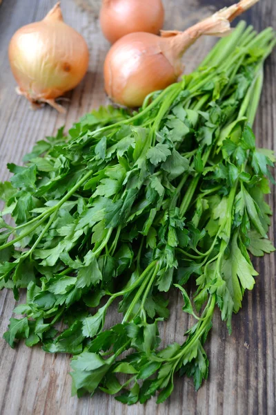 Bouquet de persil vert frais avec oignons sur table en bois — Photo