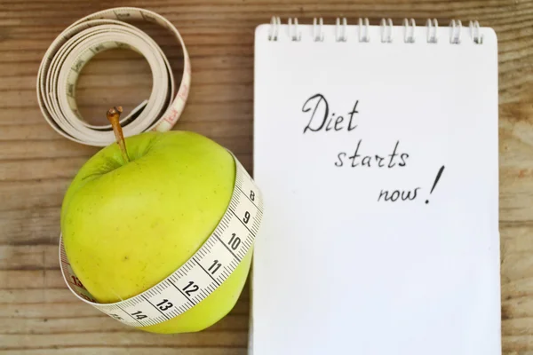 Ernährungskonzept mit grünem Apfel, Notizbuch und Maßband auf Holztisch — Stockfoto